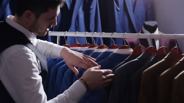 Joven eligiendo traje clásico en la tienda de trajes — Vídeos de Stock