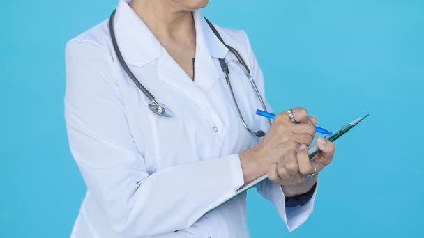 Mavi bir arka plan üzerinde pozitif orta yaşlı bir kadın doktor — Stok video
