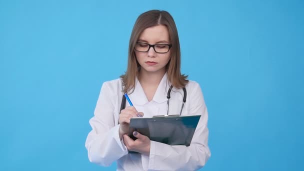 Jovem médica de casaco branco com prancheta — Vídeo de Stock