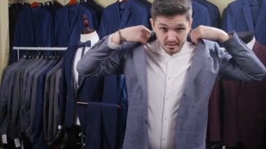 Adam mağazada takım elbise giyer.