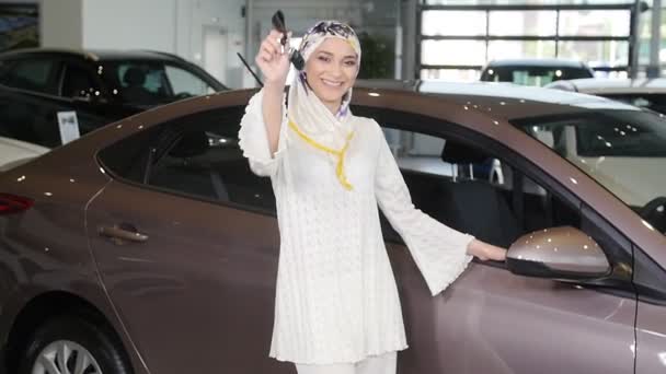 Мусульманка с ключом от машины на фоне автомобильного шоу — стоковое видео