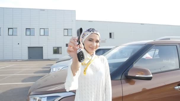 Muslim woman in hijab with car key outdoors — Stock Video