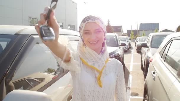 Muslim woman in hijab with car key outdoors — Stock Video