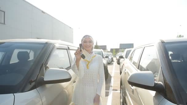 Muslim woman in hijab with car key outdoors — Stock Video