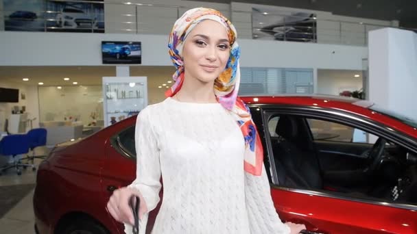Mujer musulmana con llave del coche sobre el fondo del espectáculo de coche — Vídeo de stock