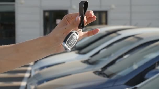 Mano con una llave en el fondo de una fila de coches nuevos — Vídeos de Stock