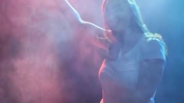 Genç modern stil dansçı duman ve ışıkları karanlık bir arka plan üzerinde