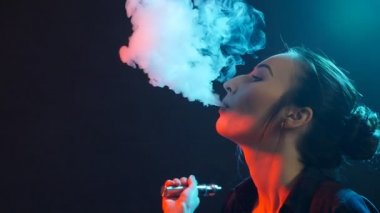 Genç kadın renk ışık elektronik sigara içiyor. Gece hayatı ve vape kavramı