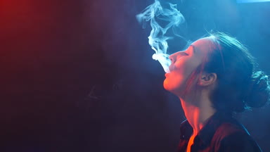 Genç kadın renk ışık elektronik sigara içiyor. Gece hayatı ve vape kavramı