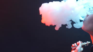 Genç kadın renk ışık elektronik sigara içiyor. Gece hayatı ve vape kavramı