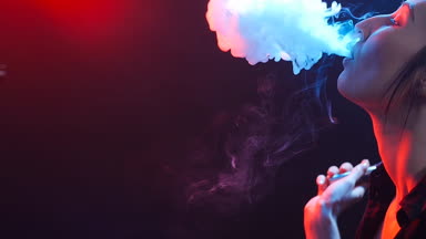 Genç kadın renk ışık elektronik sigara içiyor. Gece hayatı ve vape kavramı
