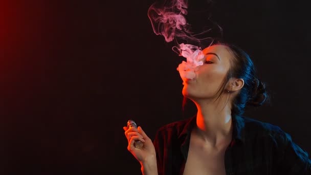 Jonge vrouw rookt elektronische sigaret in de kleur licht. Nacht leven en vape concept — Stockvideo