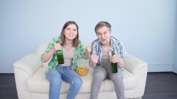 Молодая пара смотрит спорт дома по телевизору — стоковое видео