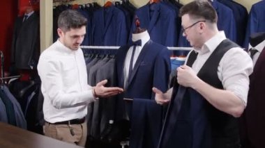 Bir adam mağazadan takım elbise alıyor.