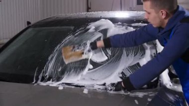 Adam çalışan çamaşır araba sünger bir araba yıkama istasyonu ile