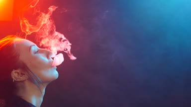 Glamour baştan çıkarıcı muhteşem bir esmer kadın sigara elektronik sigara neon renkli stüdyoda ışık portresi