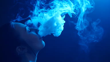 Glamour baştan çıkarıcı muhteşem bir esmer kadın sigara elektronik sigara neon renkli stüdyoda ışık portresi