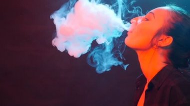 Glamour baştan çıkarıcı muhteşem bir esmer kadın sigara elektronik sigara neon renkli stüdyoda ışık portresi