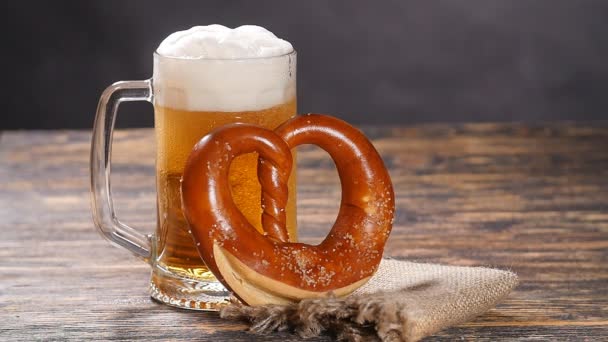Um copo de cerveja e pretzel em uma mesa de madeira — Vídeo de Stock