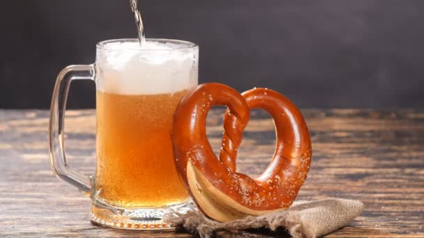 Un vaso de cerveza y pretzel sobre una mesa de madera — Vídeos de Stock