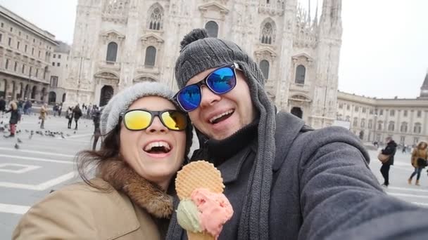 Gelukkige paar in Milaan eten ijs nemen selfie zelfportret foto op vakantie reizen in Italië. Winter vakantie concept — Stockvideo