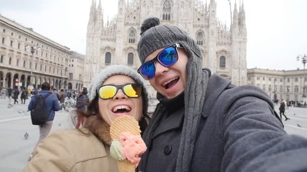 Šťastný pár v Miláně jíst zmrzlinu s selfie autoportrét foto na dovolenou jezdí v Itálii. Zimní dovolená koncept — Stock video