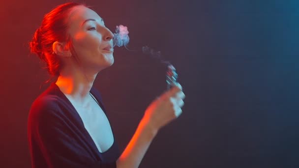 Une jeune femme fume une cigarette électronique. Fumer dans la lumière de couleur — Video