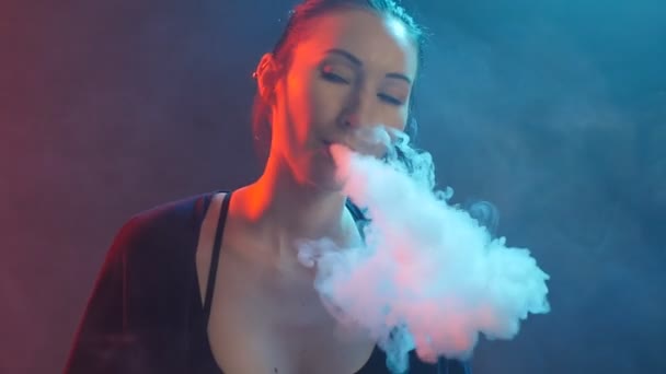 Una joven fuma un cigarrillo electrónico. Fumar en luz de color — Vídeos de Stock