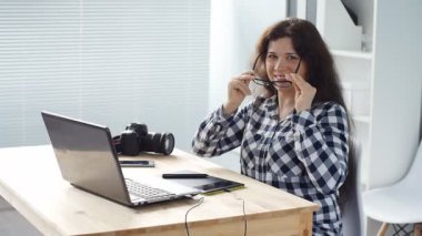 Ofiste bilgisayar üzerinde çalışan gülümseyen kadın tasarımcı