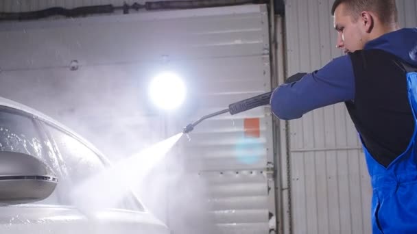 Man wassen auto onder hoge druk water binnenshuis — Stockvideo