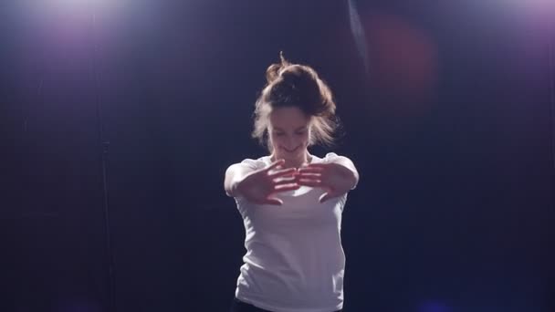 Молодая женщина танцует на черном фоне — стоковое видео