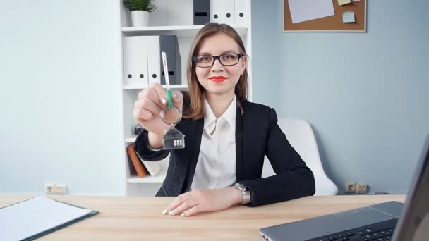 Jonge vrouw makelaar glimlachend overhandigt de sleutels tot nieuwe onroerend goed — Stockvideo