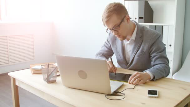 Jonge man ontwerper in glazen werken op een grafisch tablet — Stockvideo