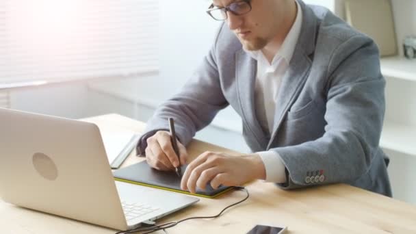 Junger Mann mit Brille arbeitet an einem Grafik-Tablet — Stockvideo