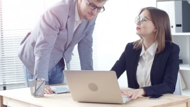 Jovem apontando para laptop discutindo algo com seu colega de trabalho enquanto estava no escritório — Vídeo de Stock