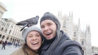 Mutlu turist ve telefon ile kendi kendine portre önünde Duomo Katedrali, Milan alarak güvercinler. Kış seyahat kavramı