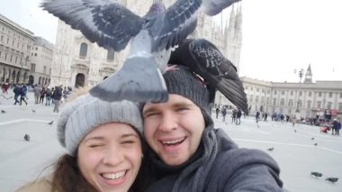 Mutlu turist ve telefon ile kendi kendine portre önünde Duomo Katedrali, Milan alarak güvercinler. Kış seyahat kavramı