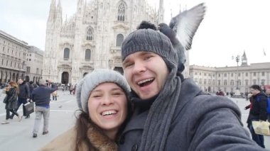 Mutlu turist ve telefon ile kendi kendine portre önünde Duomo Katedrali, Milan alarak güvercinler. Kış seyahat kavramı