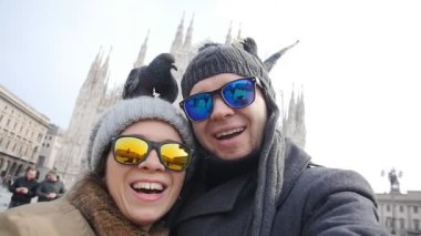 Mutlu turist ve telefon ile kendi kendine portre önünde Duomo Katedrali, Milan alarak güvercinler. Kış seyahat kavramı