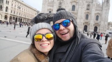 Mutlu turist ve telefon ile kendi kendine portre önünde Duomo Katedrali, Milan alarak güvercinler. Kış seyahat kavramı