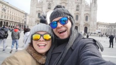 Mutlu turist ve telefon ile kendi kendine portre önünde Duomo Katedrali, Milan alarak güvercinler. Kış seyahat kavramı