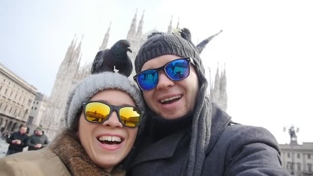 Счастливые туристы и голуби делают автопортрет с телефоном перед собором Дуомо в Милане. Концепция зимнего путешествия — стоковое видео