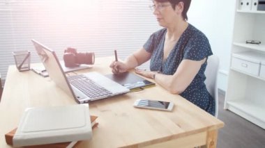 Grafik tasarımcı modern ofiste çalışırken dijital grafik tablet kullanan kadın yaşlı