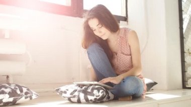 Genç kadın güneşli bir odada tablet kullanma