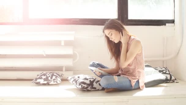 Junge Frau in einem sonnigen Raum mit einem Tablet — Stockvideo
