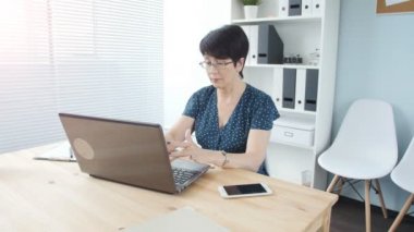 Ofiste bir dizüstü bilgisayar ile bir çekici orta yaşlı iş kadını