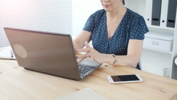Ofiste bir dizüstü bilgisayar ile bir çekici orta yaşlı iş kadını — Stok video