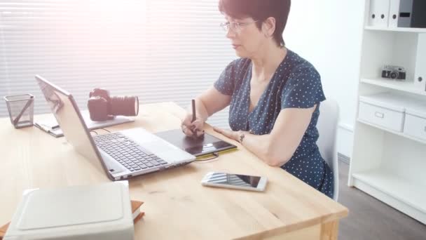 Uma mulher de negócios de meia-idade atraente com um laptop no escritório — Vídeo de Stock