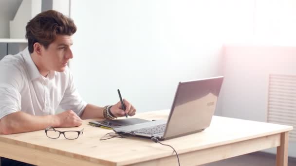 Casual mannelijke ontwerper grafisch tablet gebruiken in een heldere office — Stockvideo