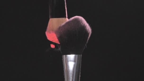 Кисти макияжа с розовым порошком на черном фоне в замедленной съемке — стоковое видео